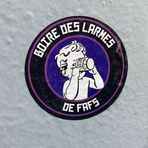 Photo d'un sticker collé sur un mur blanc. Il est rondm un dessin au milieu représente un enfant qui boit en tenant son verre de ses deux mains. Texte encadrant l'illustration : « Boire des larmes de fafs » 